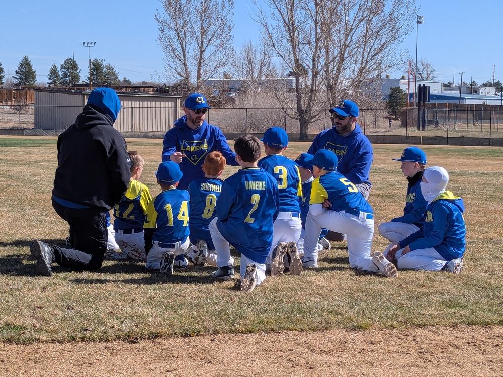 Canyon Lakers coaches meeting with players on the infield