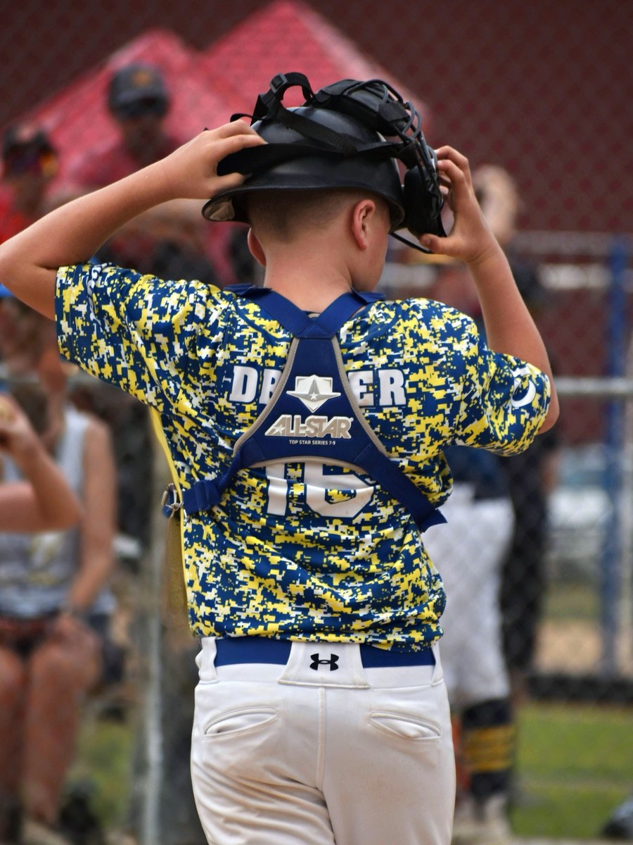 A Canyon Lakers catcher pulling his mask on before heading out