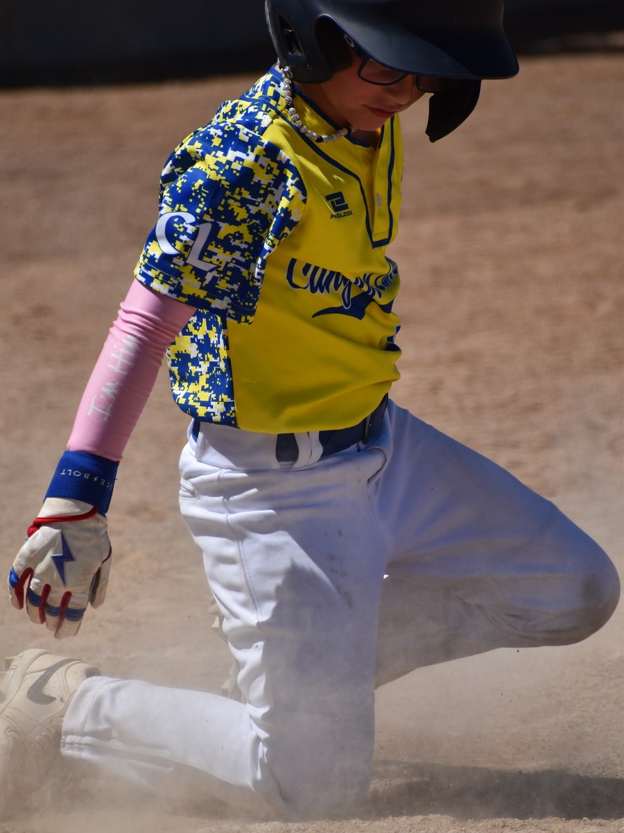A Canyon Lakers runner sliding in through a cloud of dust