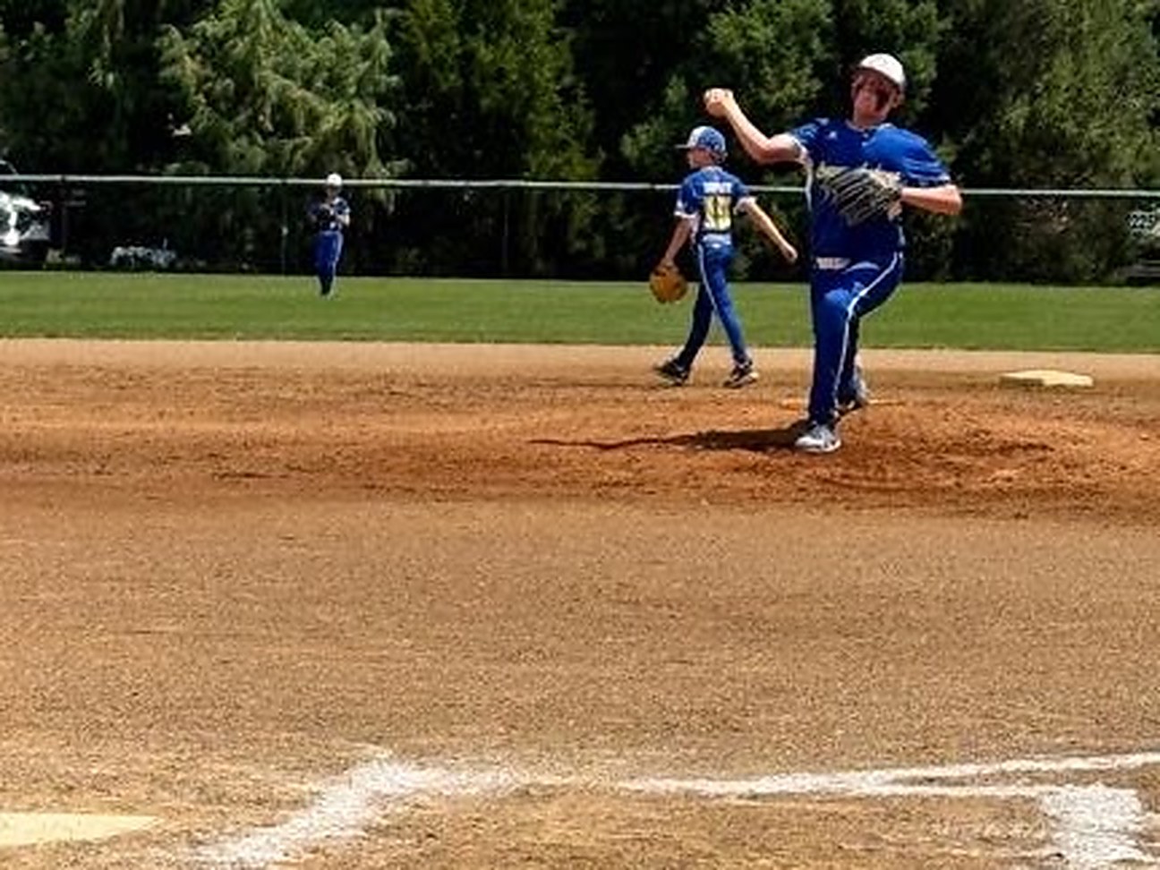 A Canyon Lakers pitcher throwing, seen from behind home plate